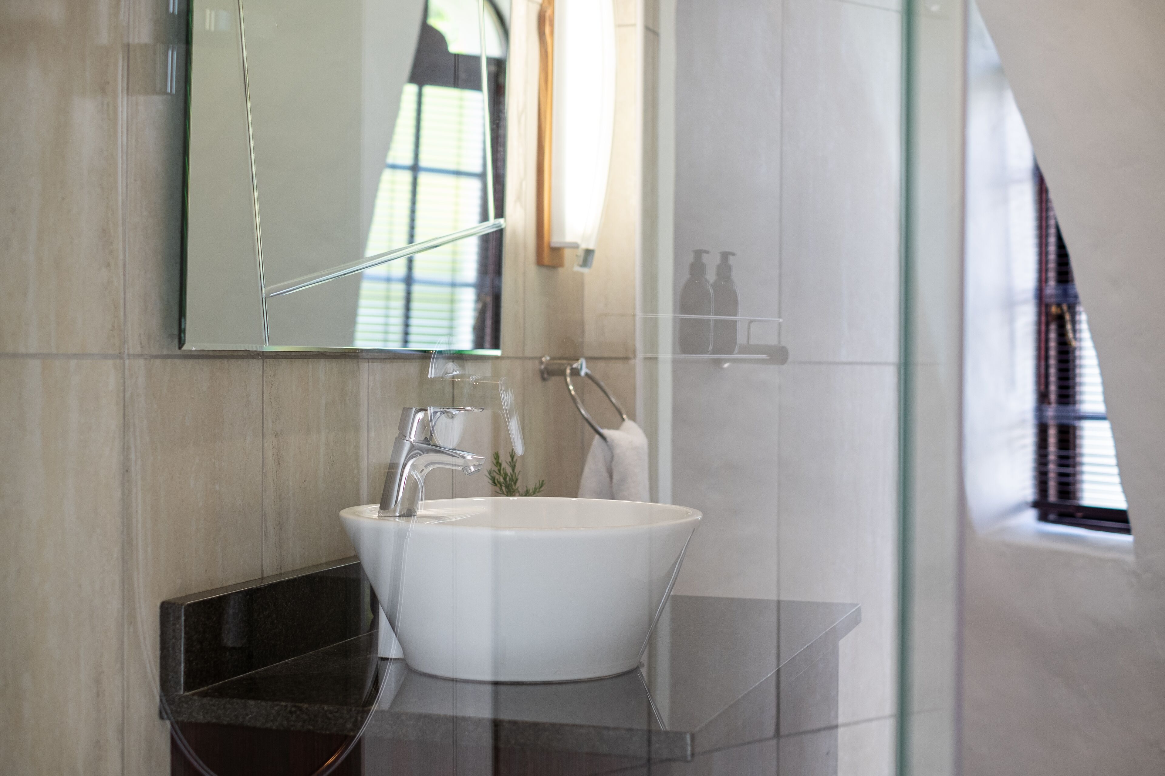 A modern bathroom with a white sink, a glass shower enclosure, and a large mirror.