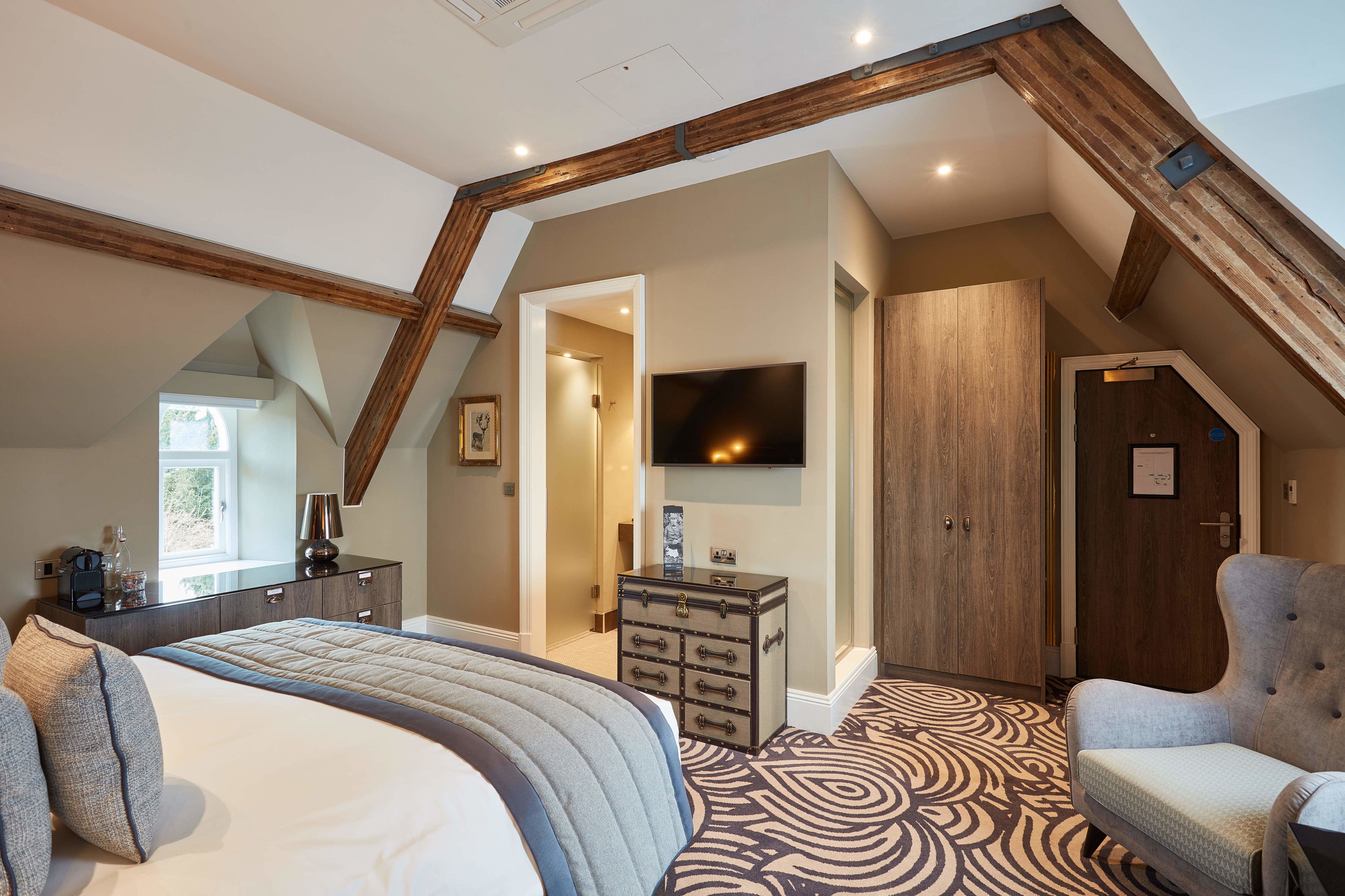 A bedroom with a large bed, a dresser, a chair, and a television.