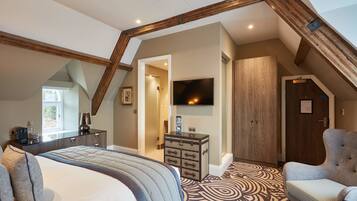 A bedroom with a large bed, a dresser, a chair, and a television.