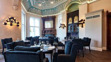 A dining area with a high ceiling, ornate ceiling design, and a large wooden bar.