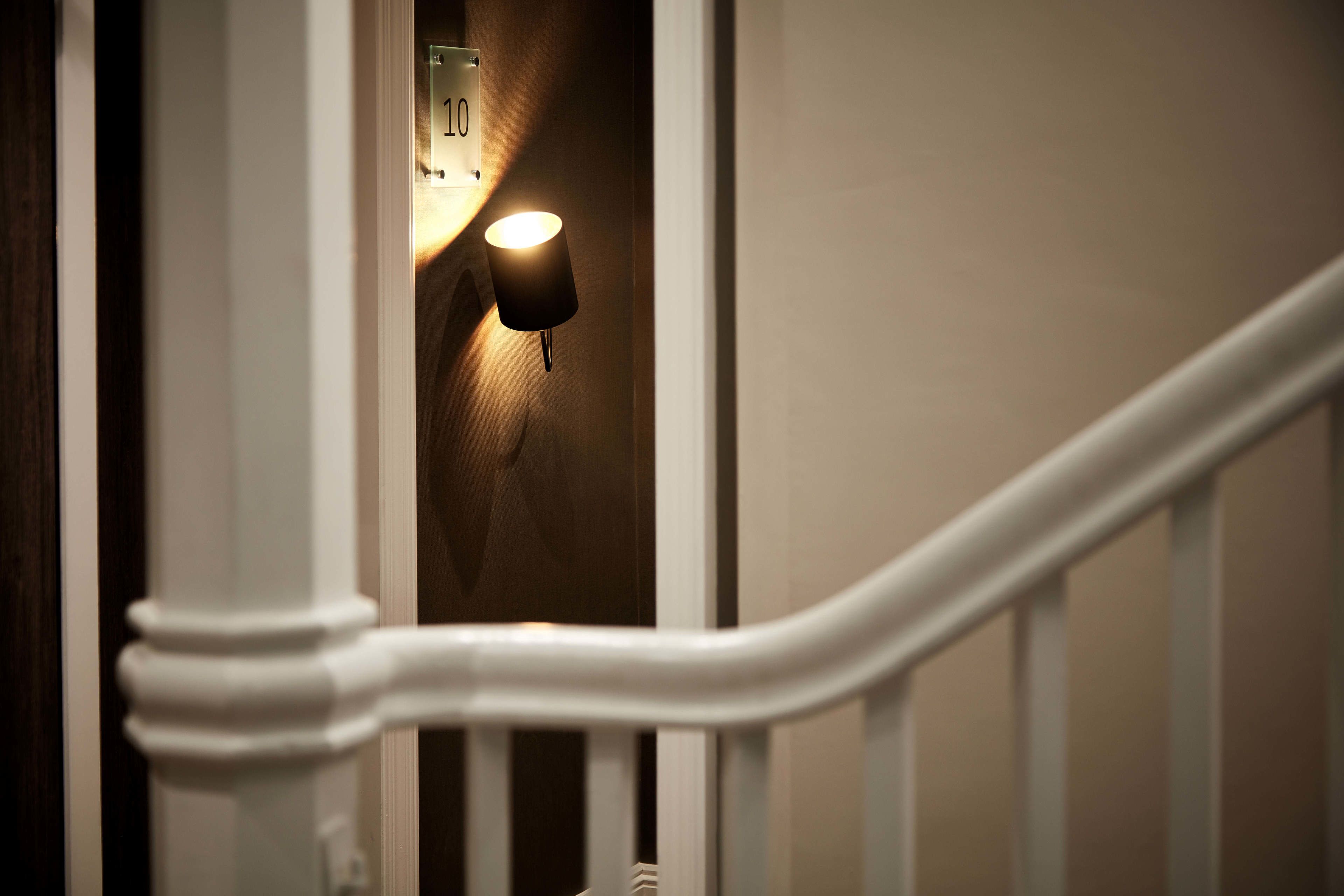 A staircase with a white handrail and a wall-mounted light fixture.