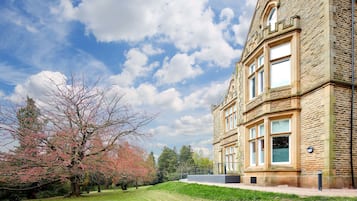 A historic stone building with large windows and a well-maintained lawn.