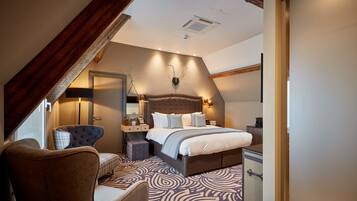 Een moderne slaapkamer met een groot bed, een stoel, een dressoir en een spiegel.