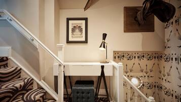 A staircase with patterned carpet, a white desk with a lamp, and a framed picture on the wall.