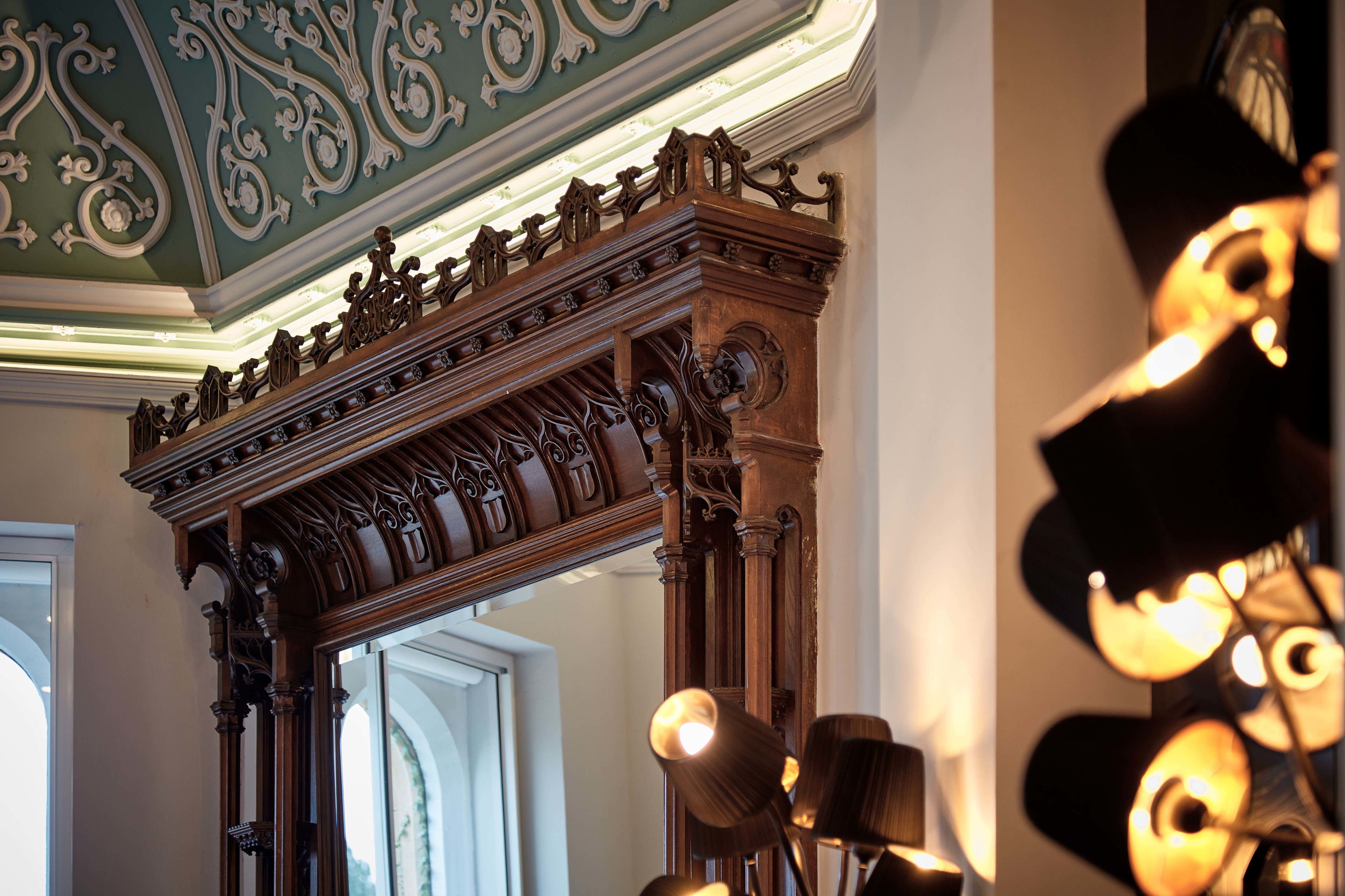 An ornate wooden staircase with intricate carvings and a green ceiling.