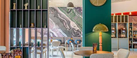 A modern cafe interior with seating, a wall clock, and a mural.