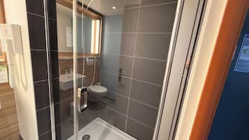 A modern bathroom with a glass-enclosed shower, a sink, and a toilet.