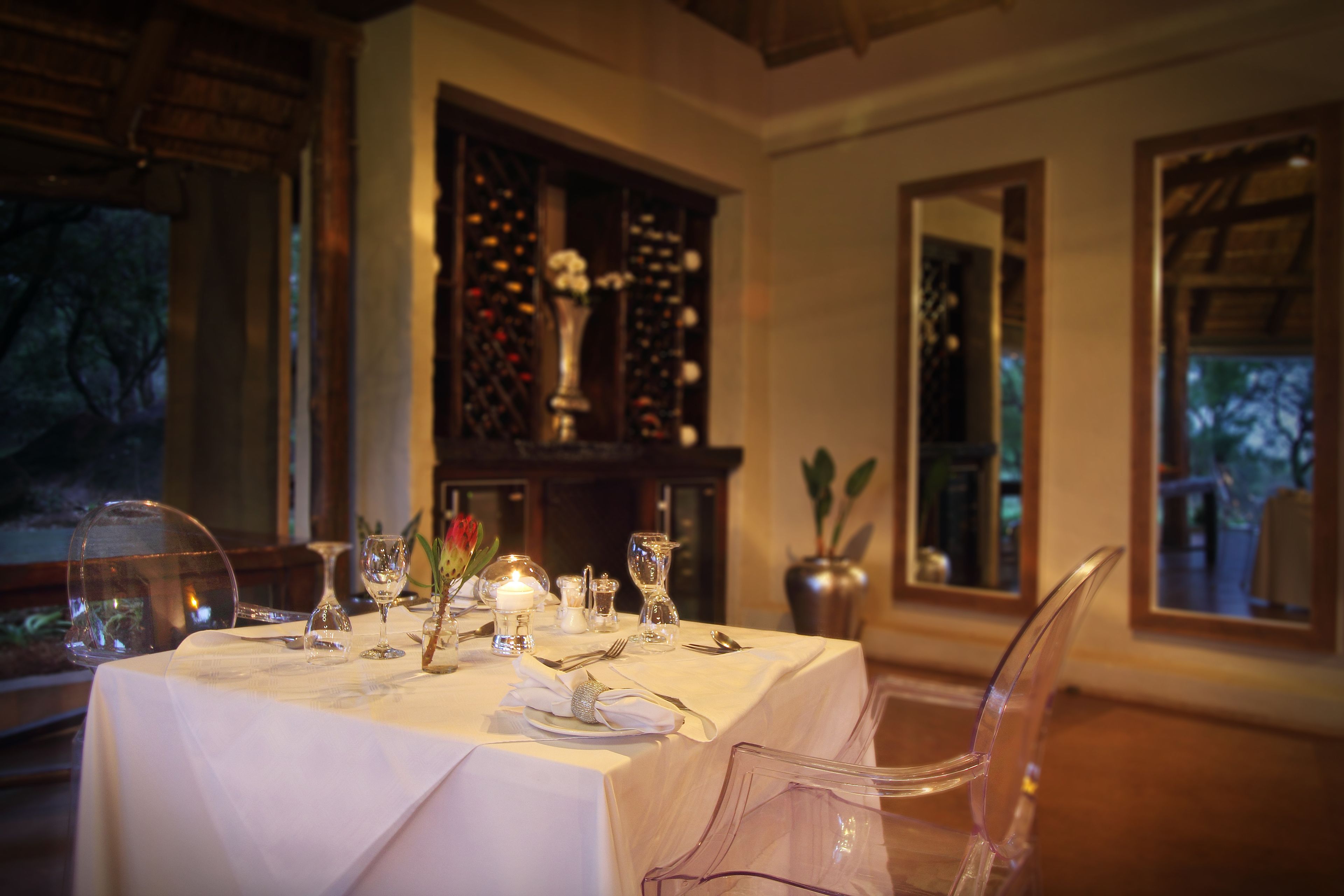 A dining table set with white tablecloth, clear glassware, and candles.