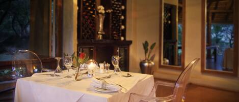 A dining table set with white tablecloth, clear glassware, and candles.