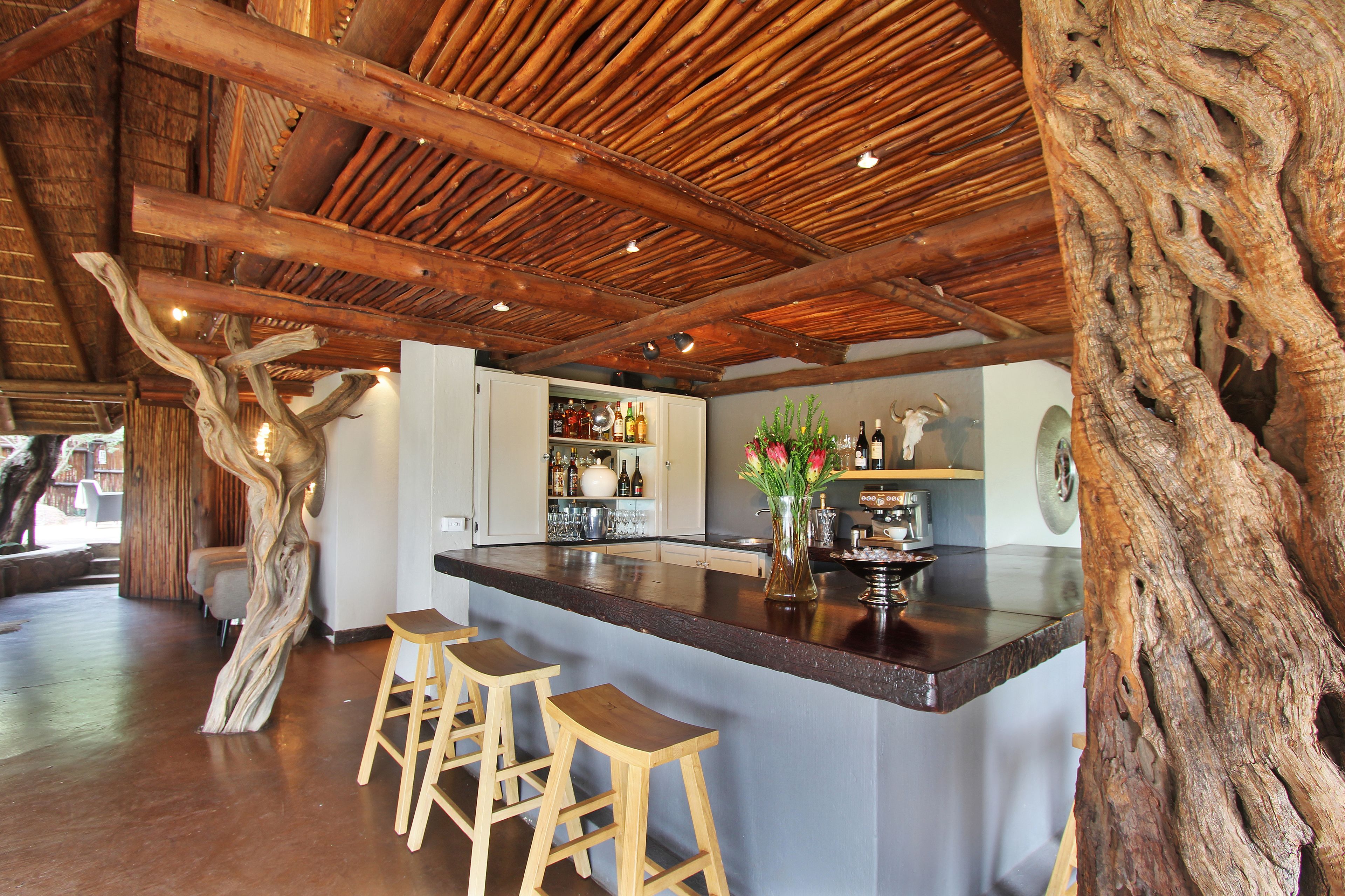 Een keuken met een centraal eiland, houten krukken en een rustiek plafond.