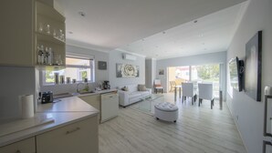 Une cuisine moderne avec un coin repas, un canapé blanc et une table basse en verre.