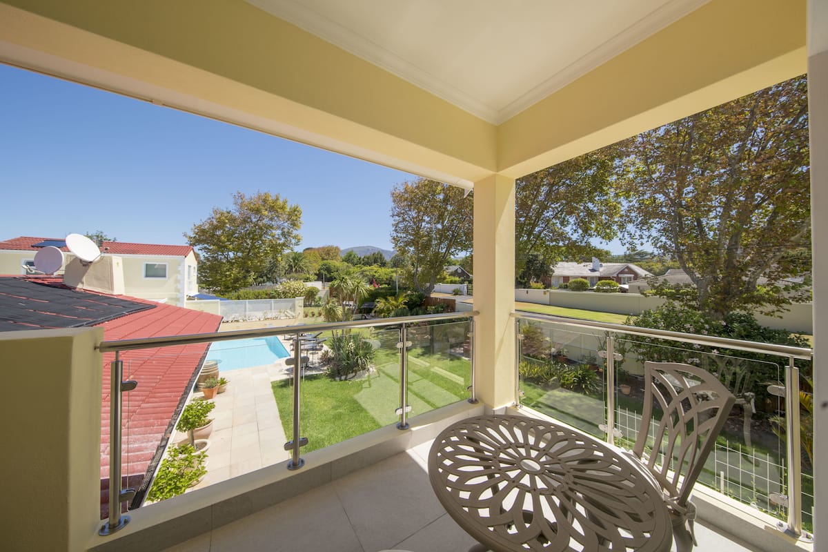 A balcony with a glass railing, a metal table, and chairs.