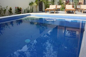 Una piscina al aire libre, tumbonas