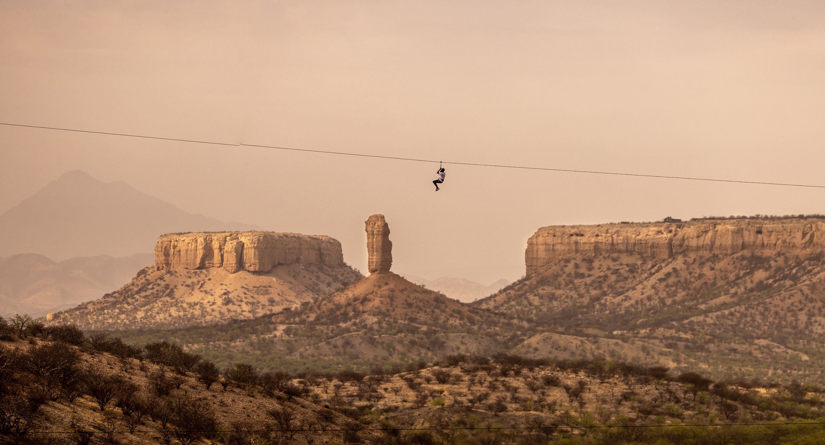 Una persona haciendo bungee jumping con un paisaje montañoso al fondo.