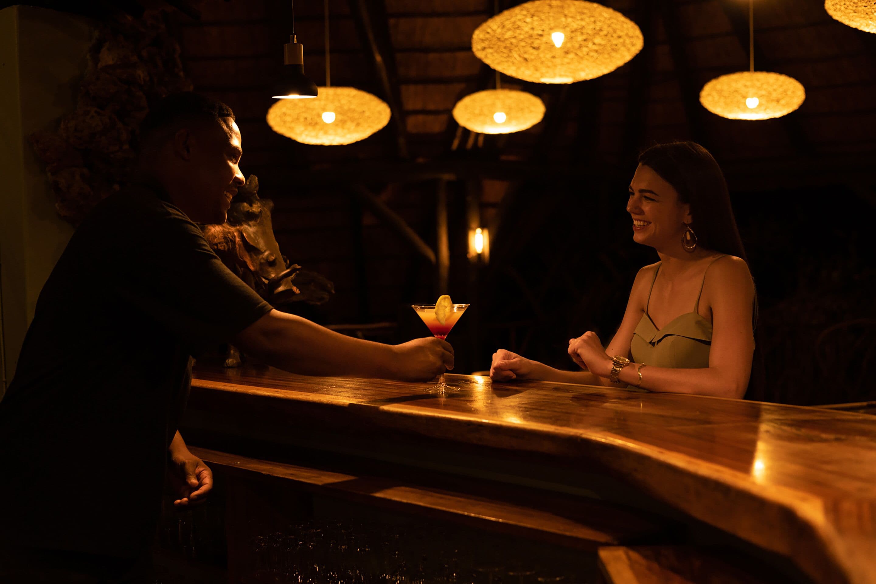 A bar area with wooden counter and hanging pendant lights.