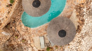 An aerial view of a swimming pool with a unique curved design, surrounded by a stone and mosaic border. - Vingerklip Lodge (Khorixas)