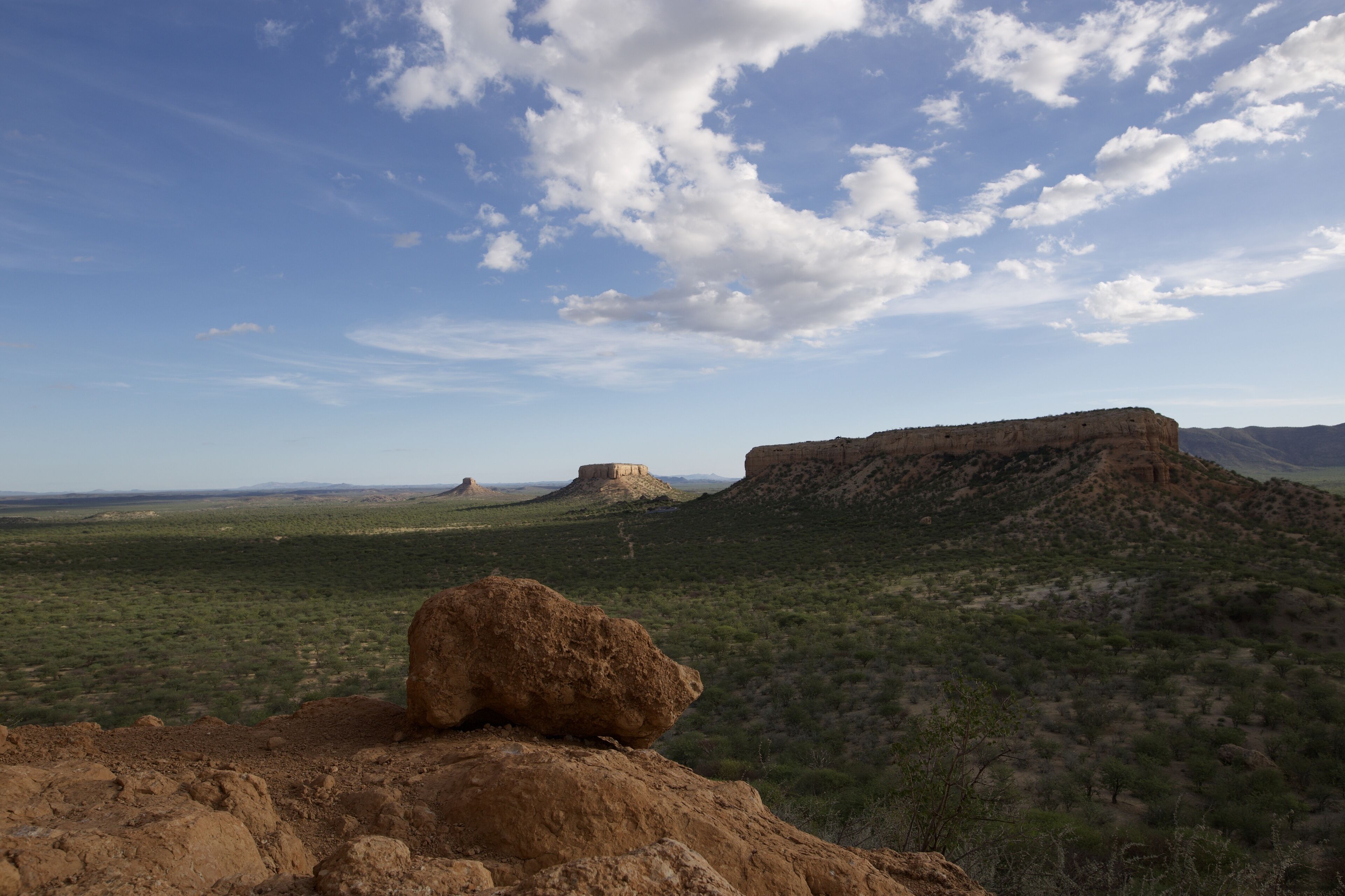 A desert landscape with rocky outcrops and sparse vegetation under a clear sky.