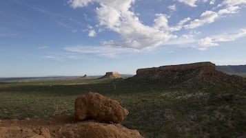 A desert landscape with rocky outcrops and sparse vegetation under a clear sky.