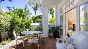 Un patio con una mesa redonda y sillas, un sofá blanco y una planta en maceta.