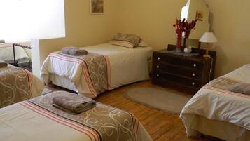 A hotel room with two beds, a dresser, a mirror, and a small table with a lamp.