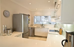 Una cocina moderna con electrodomésticos de acero inoxidable, lavavajillas y un ventanal que proporciona luz natural.