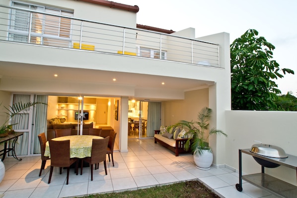 Una casa moderna de dos pisos con comedor, cocina y un balcón con parrilla.