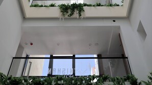 A multi-level atrium with white walls, green plants, and a central skylight. - Nishan Hotel (Amman)