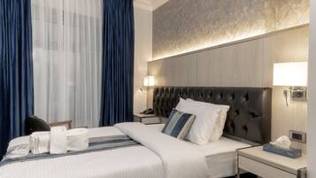Ein modernes Hotelzimmer mit einem großen Bett, einem Nachttisch, einer Lampe und einem Fenster mit Vorhängen.