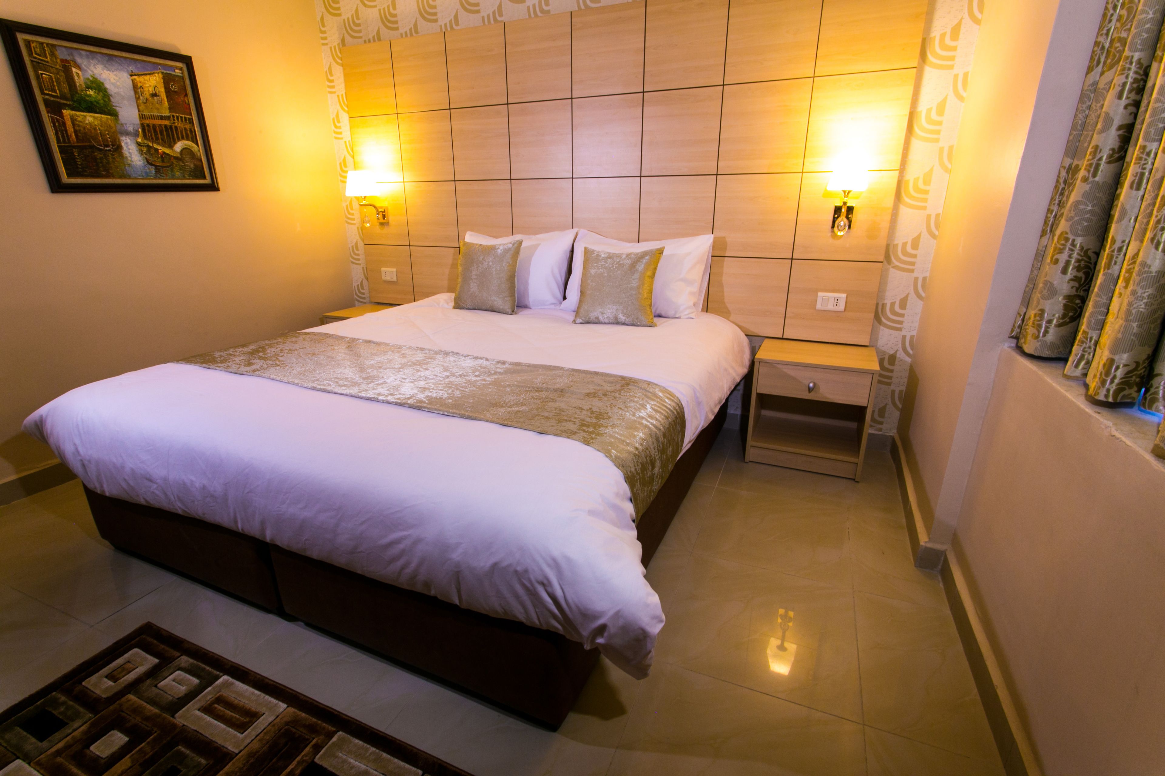 Ett hotellrum med en stor säng, två sänglampor, ett nattduksbord och en mönstrad matta.