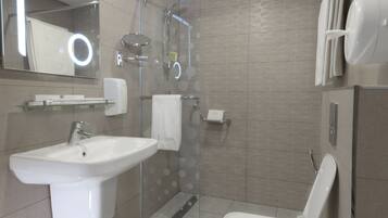 A modern bathroom with a sink, mirror, toilet, and shower.