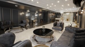 A modern lounge area with plush seating, a central coffee table, and a chandelier. - Nishan Hotel (Amman)
