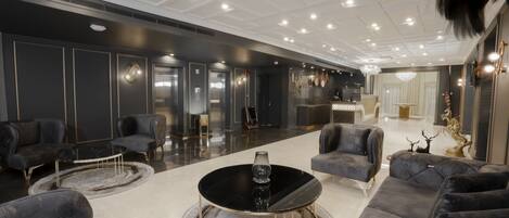 A modern lounge area with plush seating, a central coffee table, and a chandelier.