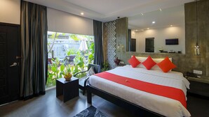 Ein modernes Hotelzimmer mit einem großen Bett, Blick auf Grün und einem Balkon.