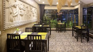 Ein Restaurant mit gemustertem Boden, Holztischen und -stühlen sowie einer dekorativen Wand.