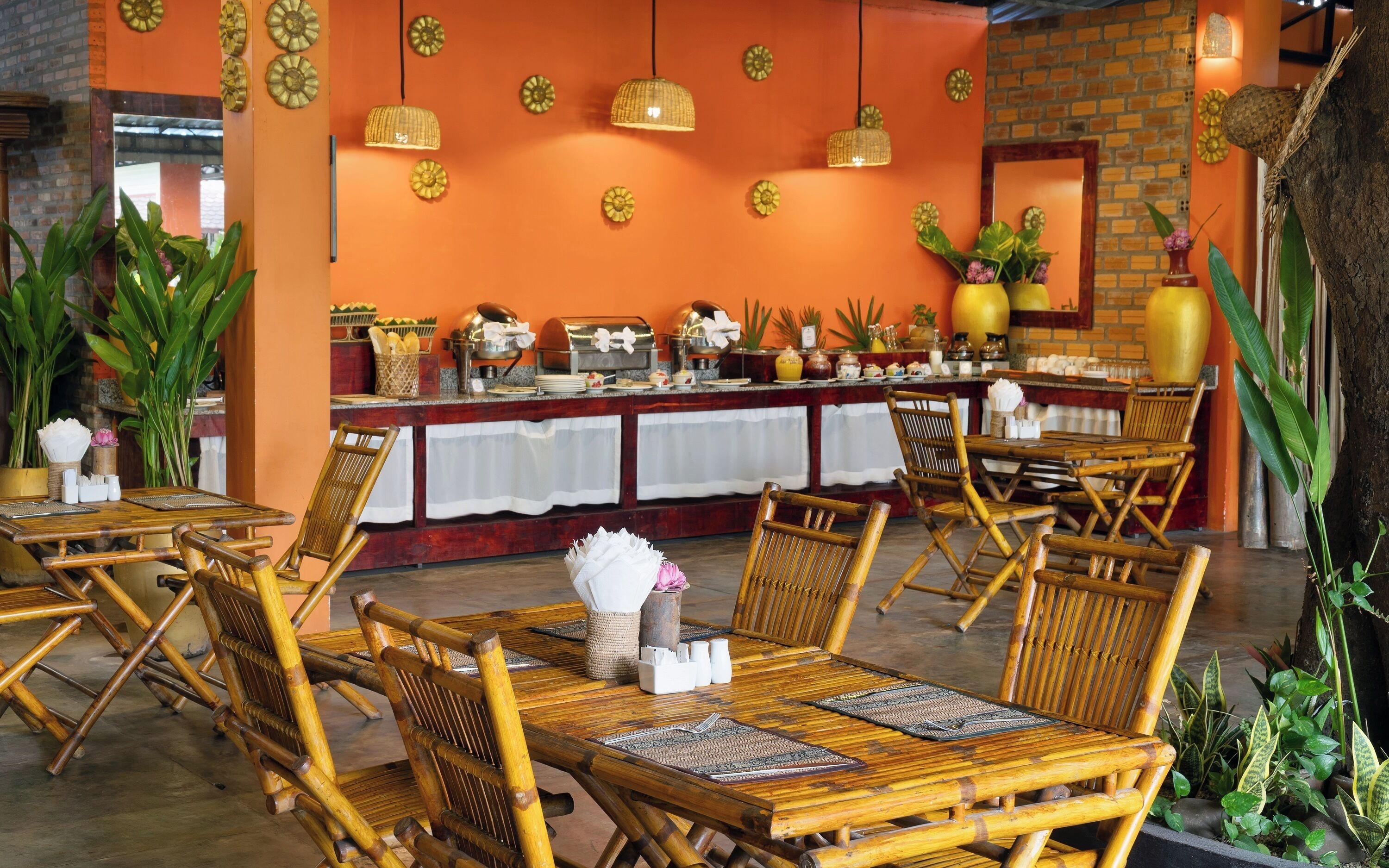 Un restaurant avec des meubles en bambou, un buffet et des œuvres d’art décoratives sur les murs.