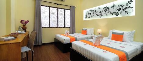 A hotel room with two beds, a desk, a chair, a window with curtains, an air conditioner, and a wall decoration.