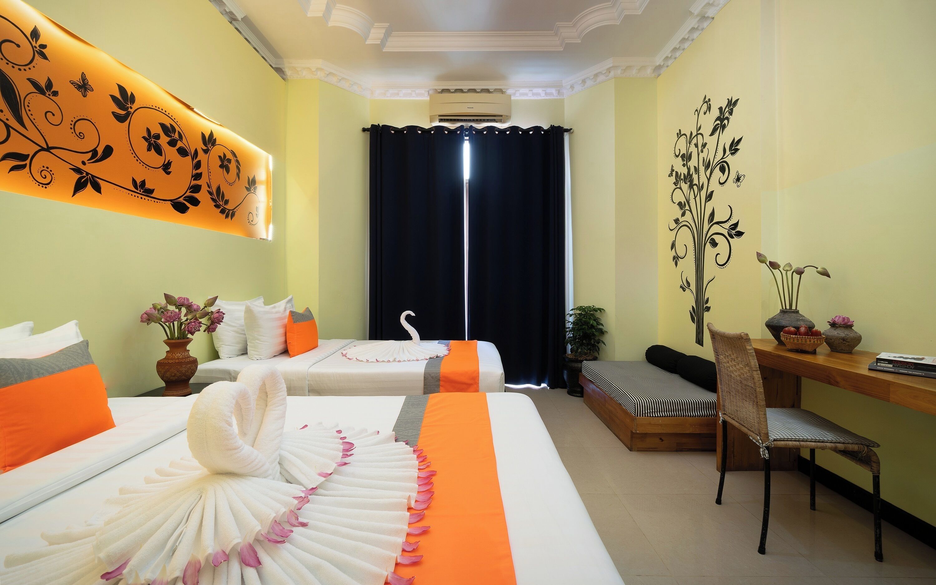 A hotel room with two beds, a desk, a chair, and a decorative wall.