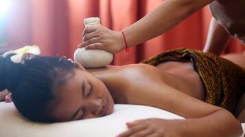 A person receiving a massage with a stone on their back.