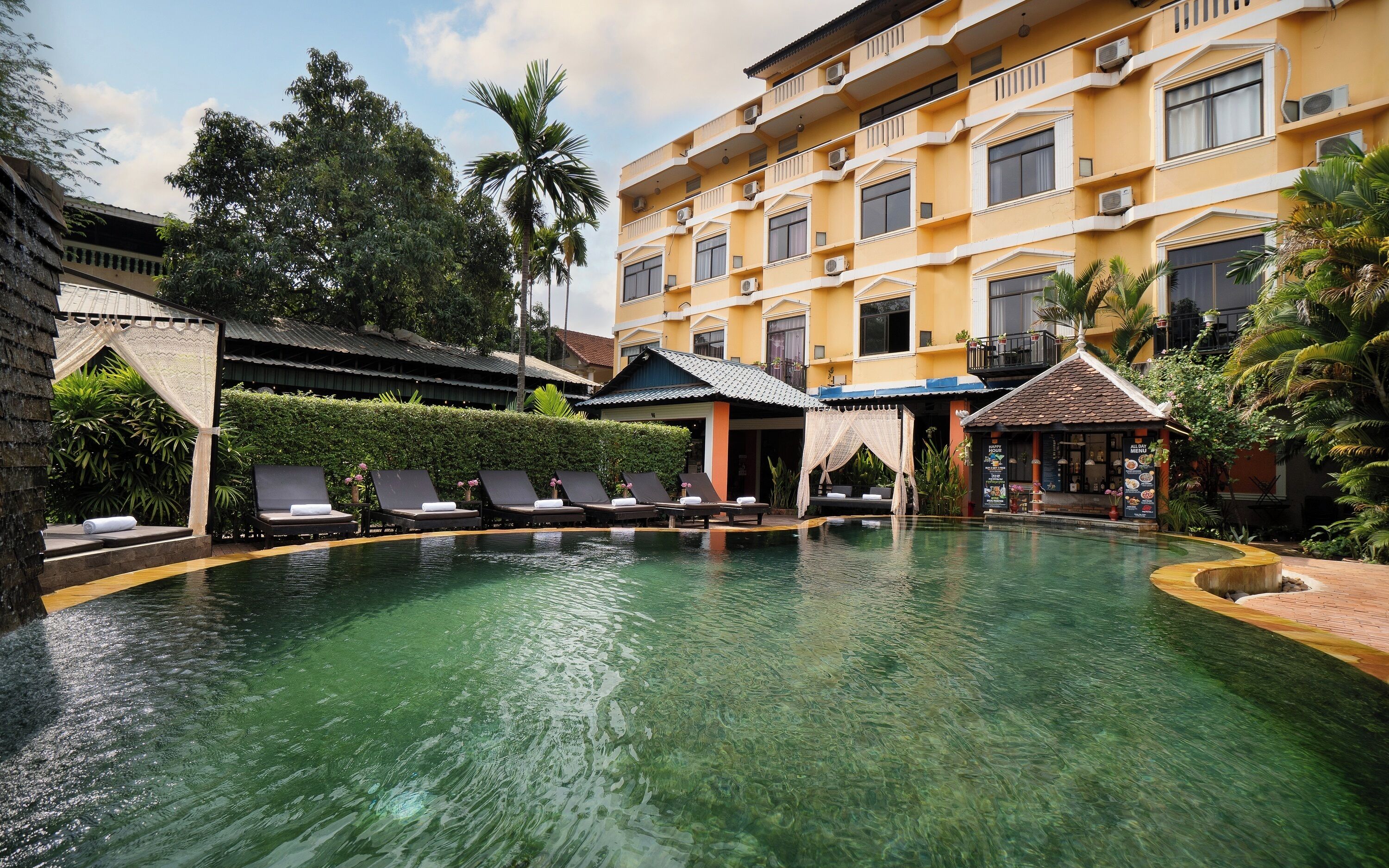 Un hotel con piscina, sillas de descanso y restaurante.