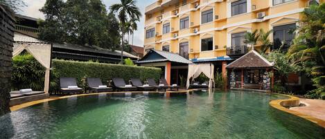 Un hotel con piscina, sillas de descanso y restaurante.