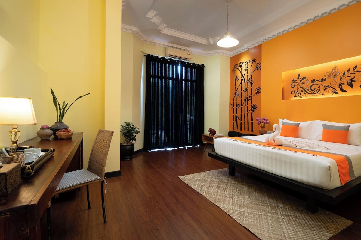 Een hotelkamer met een bed, bureau, stoel en een potplant.