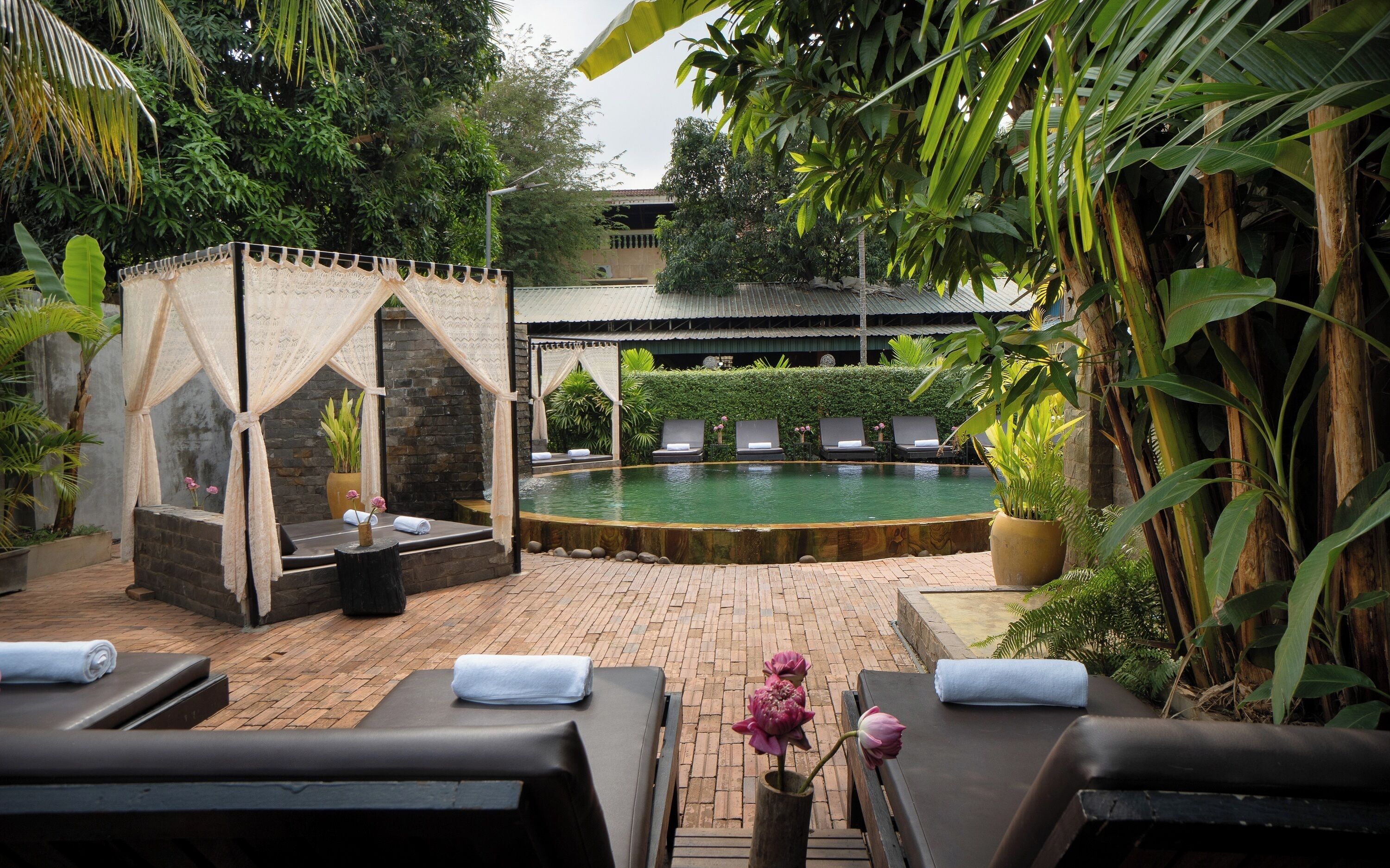 A poolside area with lounge chairs, a small gazebo, and a pool.