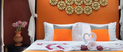 Una habitación de hotel con una cama, una decoración en la pared, un jarrón con flores y una colcha con la palabra 'HONEYMOON'.