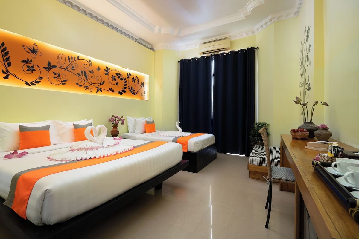 Een hotelkamer met twee bedden, een eettafel, een vaas met bloemen en een wand met bloemenmotief.