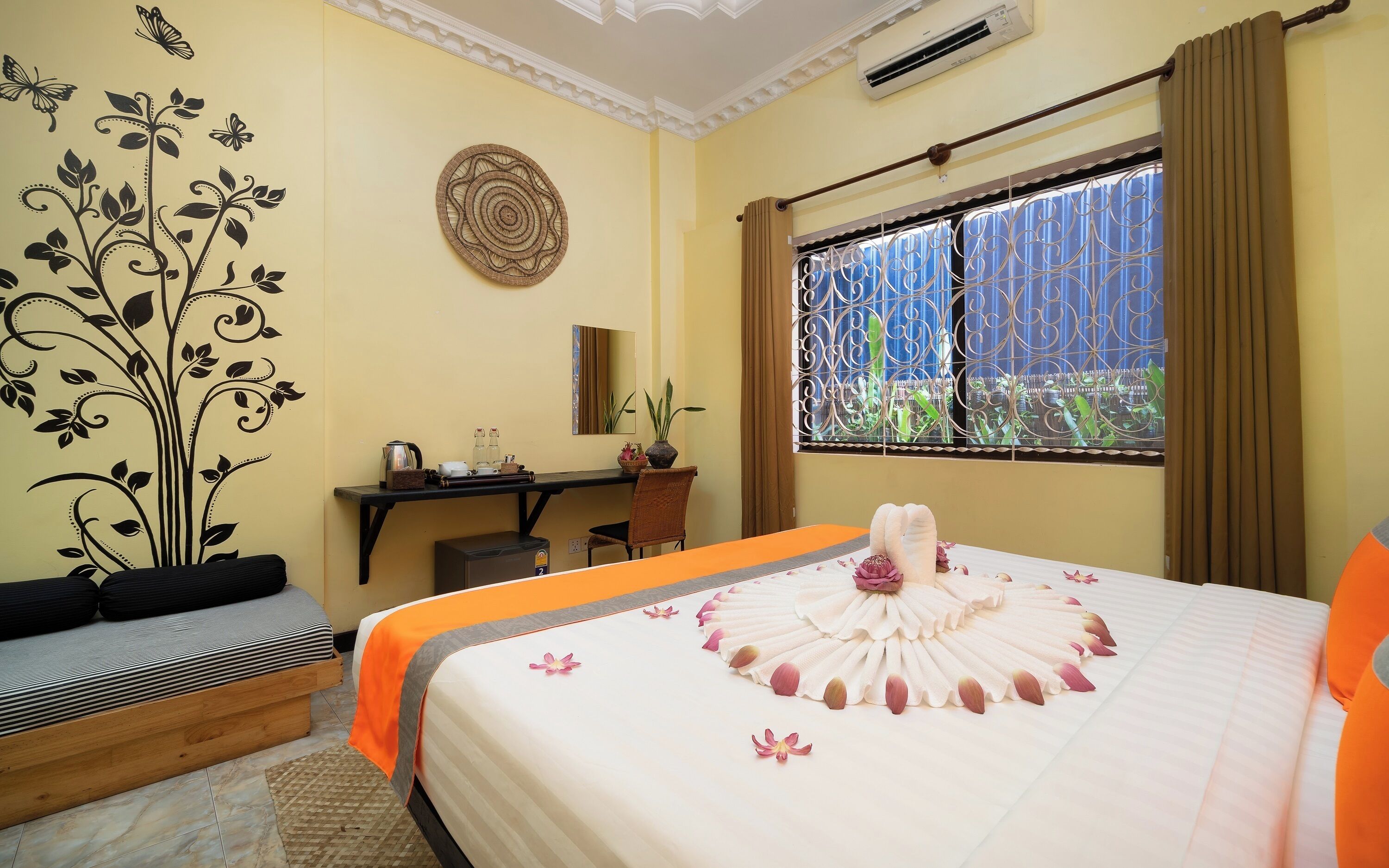 Una habitación de hotel con cama, escritorio, silla, pared decorativa y ventana con cortinas.