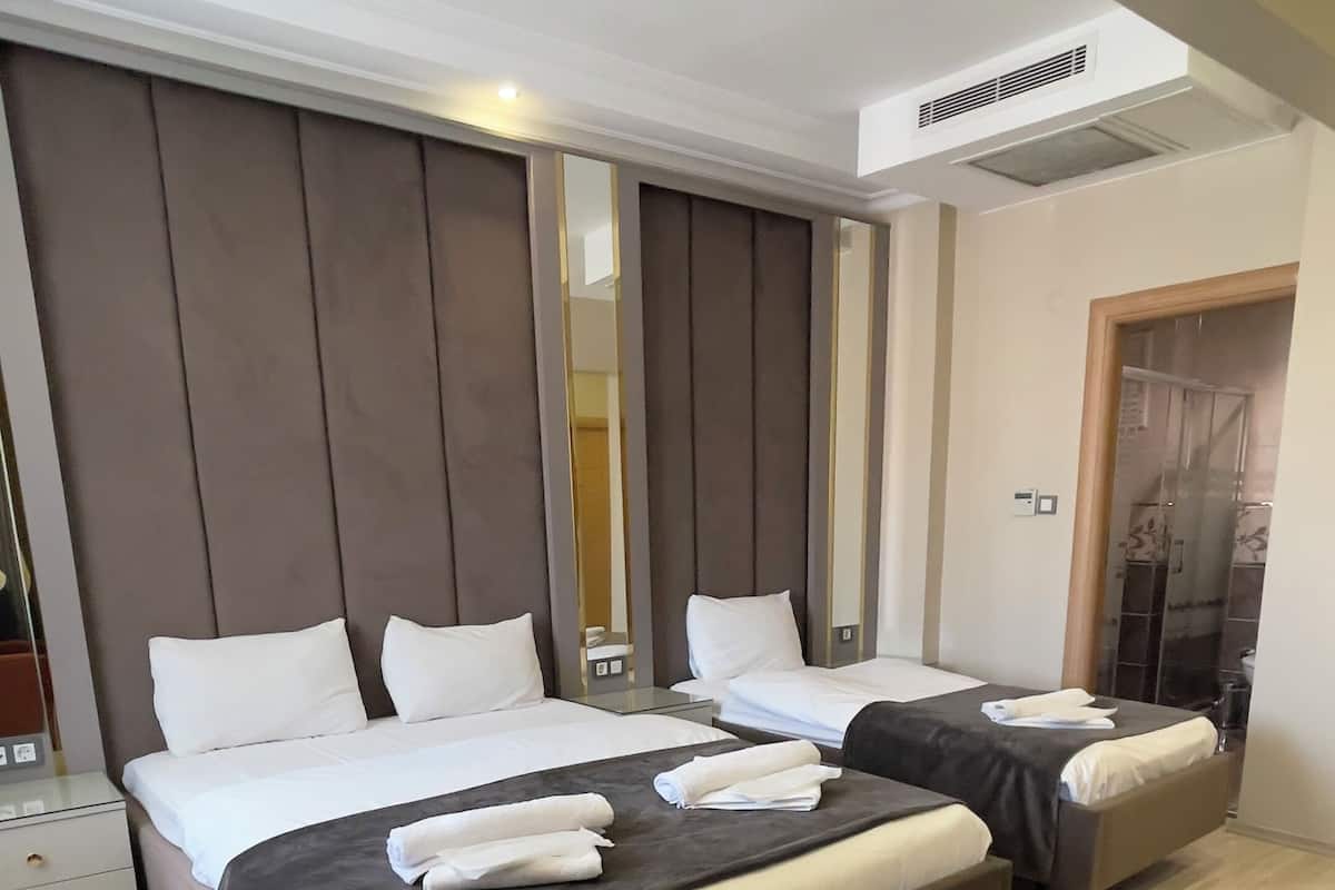 A modern hotel room with two beds, a large mirror, and a wooden floor.