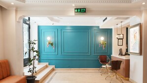 A reception area with teal walls, a reception desk, a potted plant, and a seating area with a sofa. - Reyyan Hotel (Istanbul)