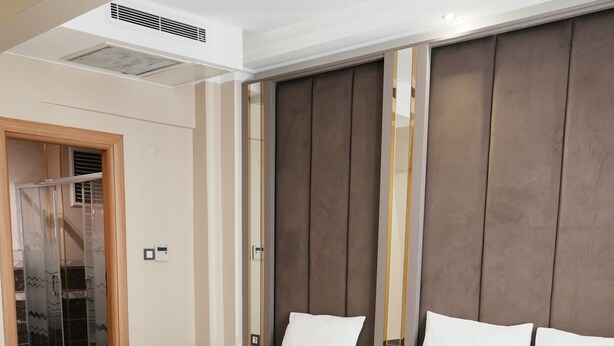 A hotel room with two beds, a large mirror, and a wooden wardrobe. - Reyyan Hotel (Istanbul)