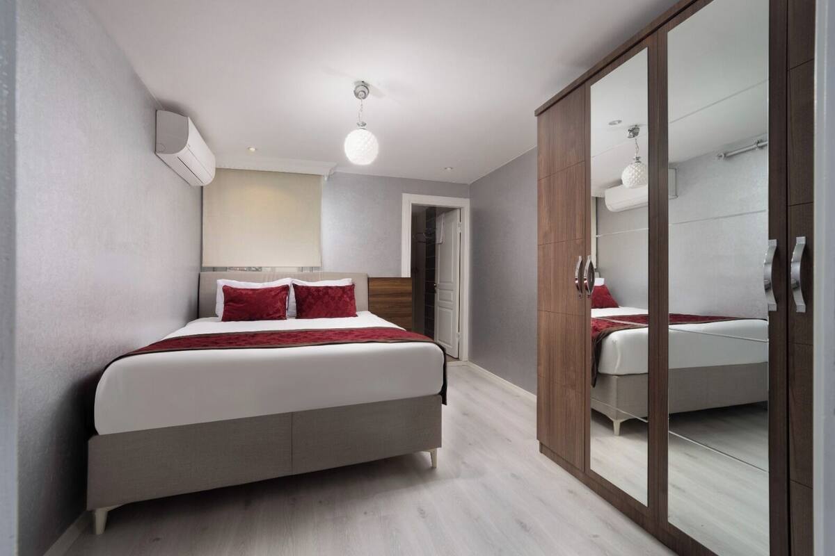 A bedroom with a bed, a wardrobe, and a mirror.