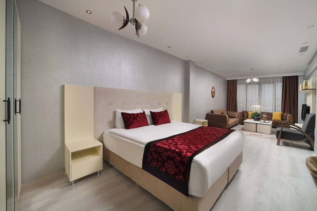 A hotel room with a large bed, a sofa, a desk, and a TV.